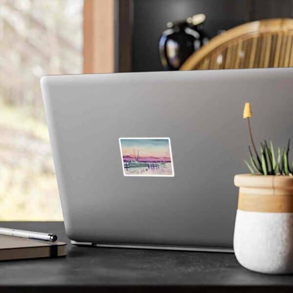 Modern laptop with a scenic travel photo sticker, desk setup, and indoor natural light.