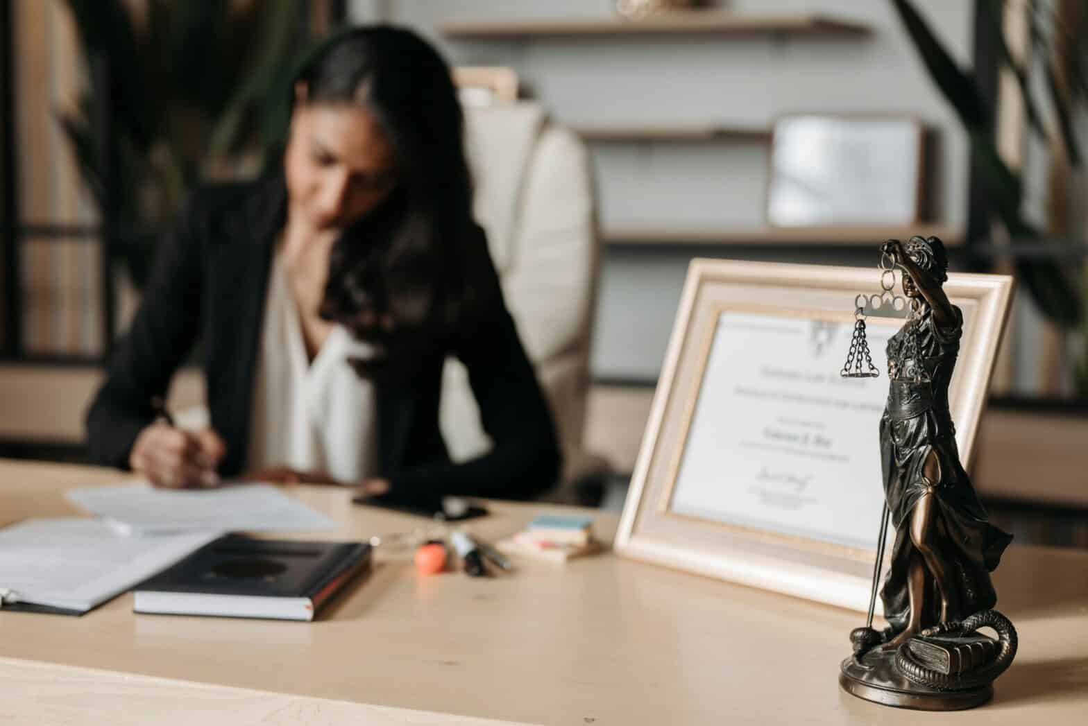 Lawyer working at desk in an office with legal symbols and certificate for legal services.